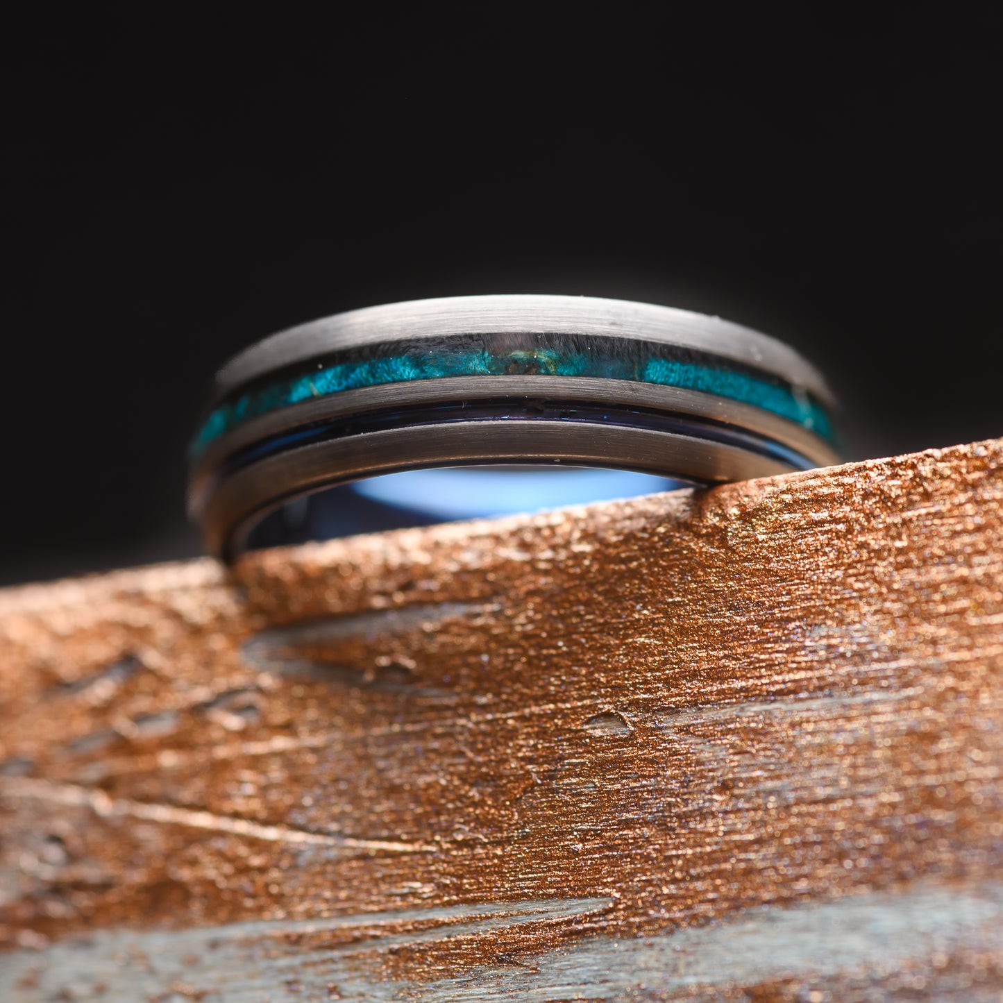 A Canadian Maple Wood and Tungsten Steel Dual Groove ring balanced on a piece of wood