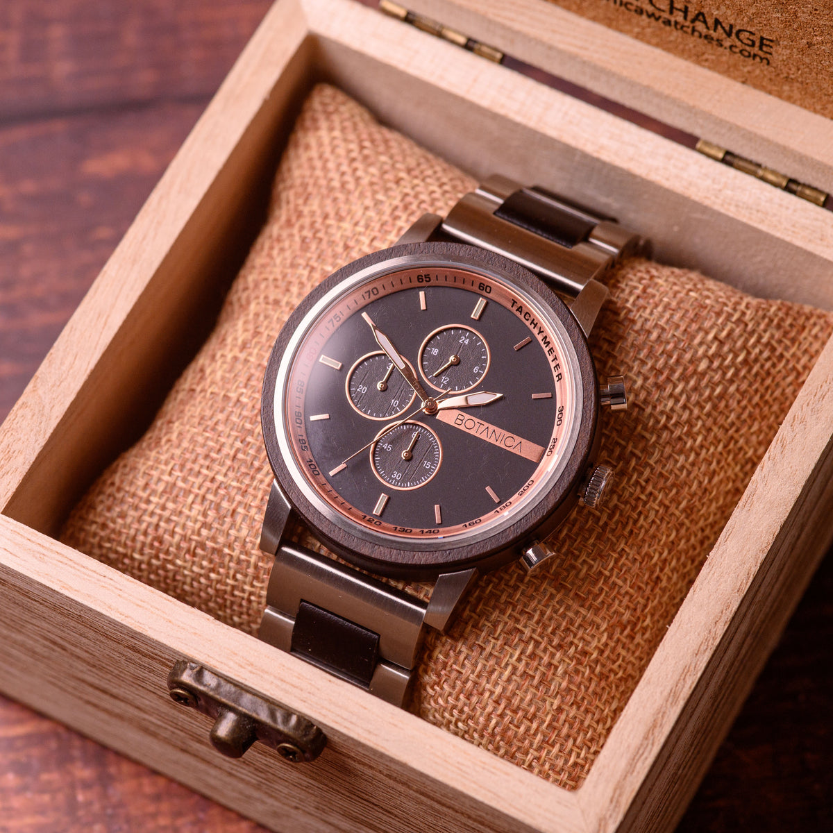 Sandalwood Watch with Black Face and subdials with rosegold bezel in a wood box on a wooden table backdrop