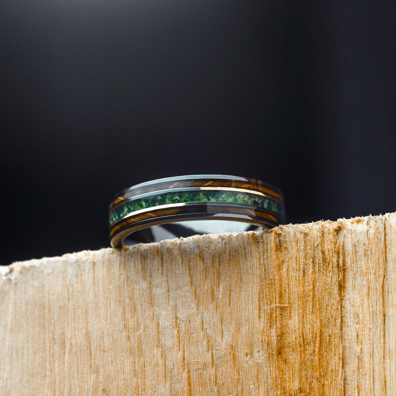 Ring with Moss Agate & Koa Wood on a wooden block against a dark background