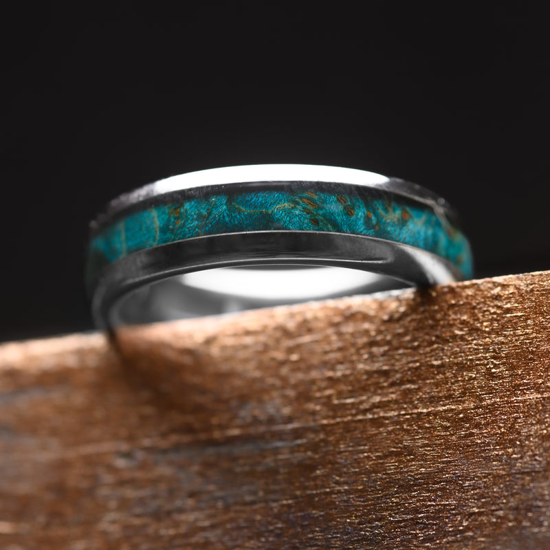 A Silver Tungsten Steel single groove ring with Canadian Maple inlay 6mm resting on a worktop bench