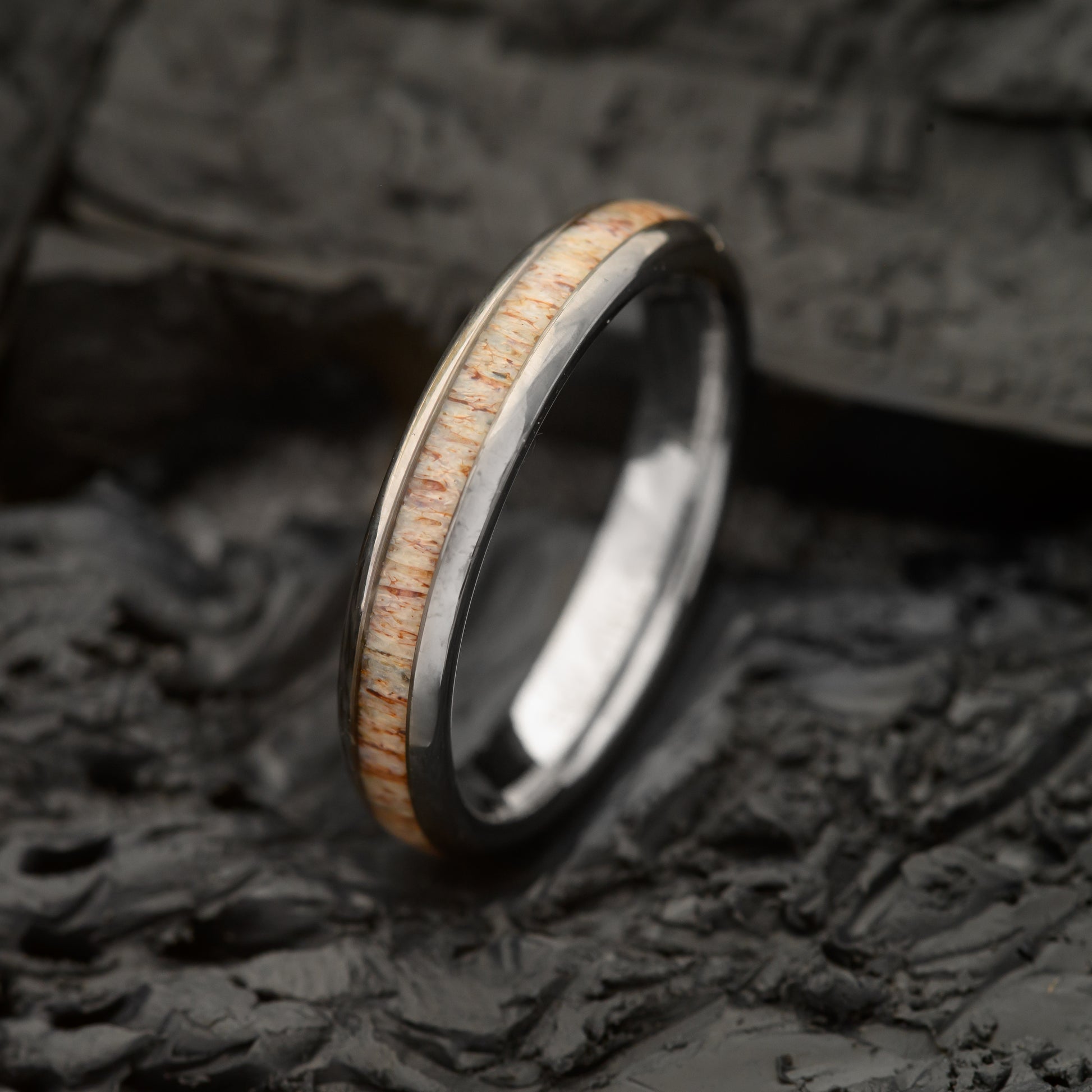 A Silver Tungsten Steel ring 4mm with single groove deer antler resting on a charcoal bed