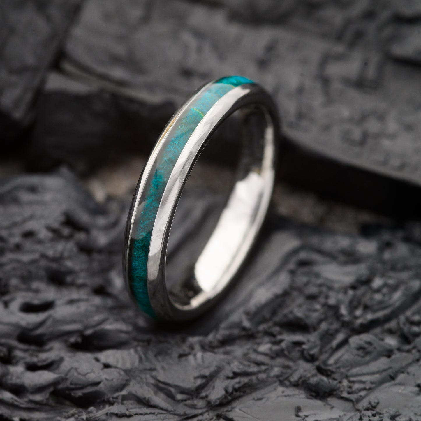 A womens 4mm tungsten ring with maplewood inlay sitting on a charcoal base
