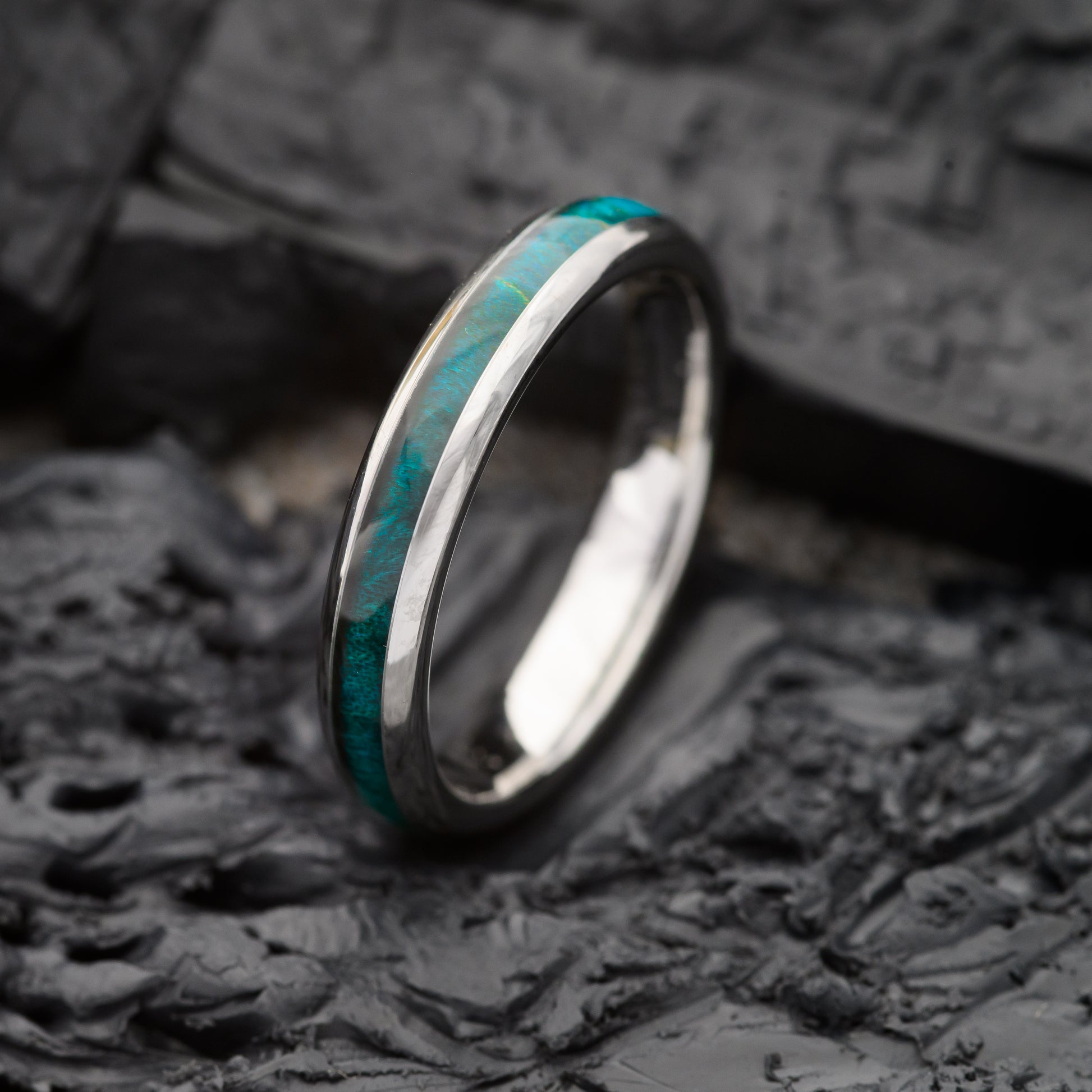 A womens 4mm tungsten ring with maplewood inlay sitting on a charcoal base