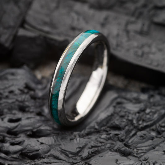A womens 4mm tungsten ring with maplewood inlay sitting on a charcoal base