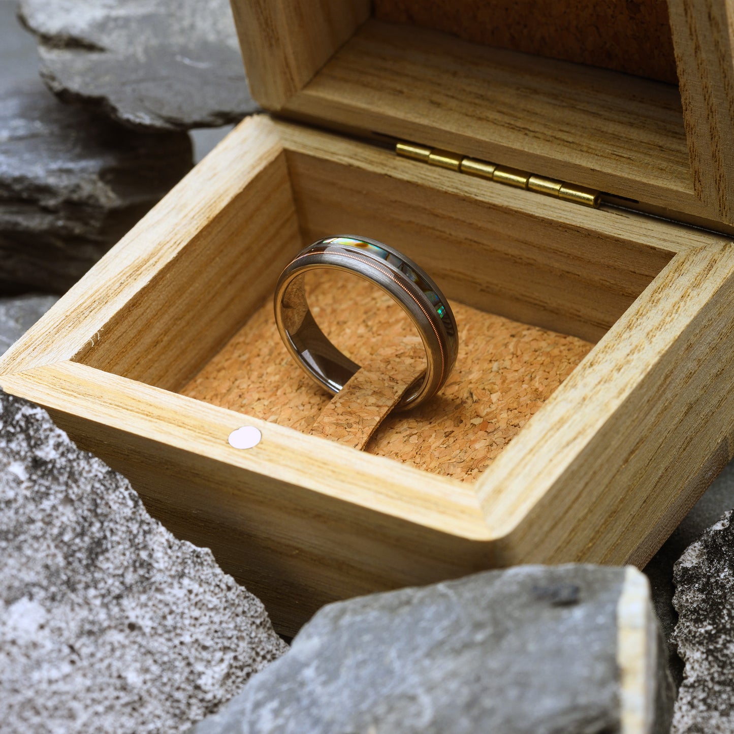 Silver ring in a wooden box with a natural stone background