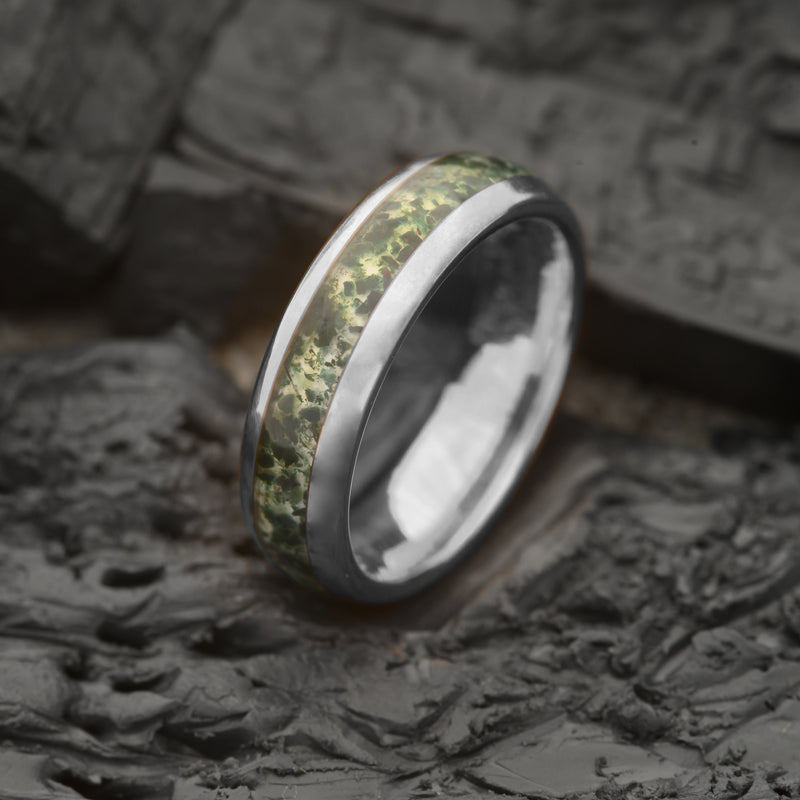 A 6mm silver tungsten ring with an inset strip of natural moss agate, displayed on a textured dark background.
