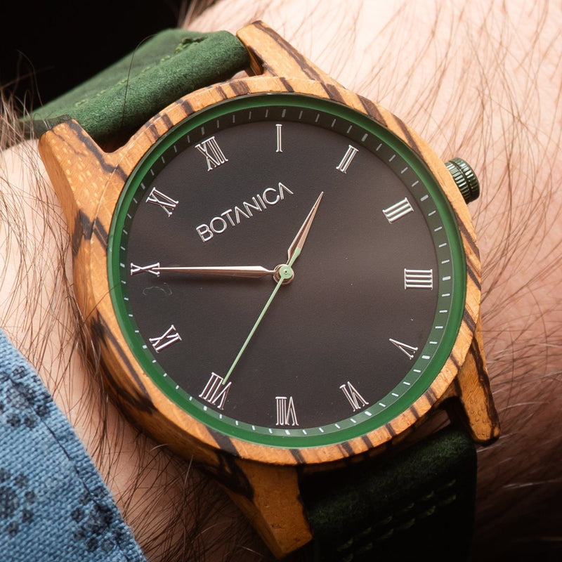 A wooden watch with a green band and dial, featuring Roman numerals and the brand name 'Botanica'.