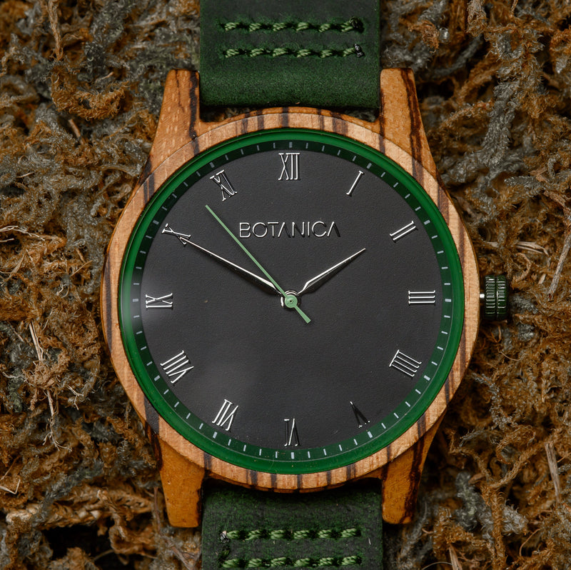 Wooden Watch with black face and green leather strap on mossy texture