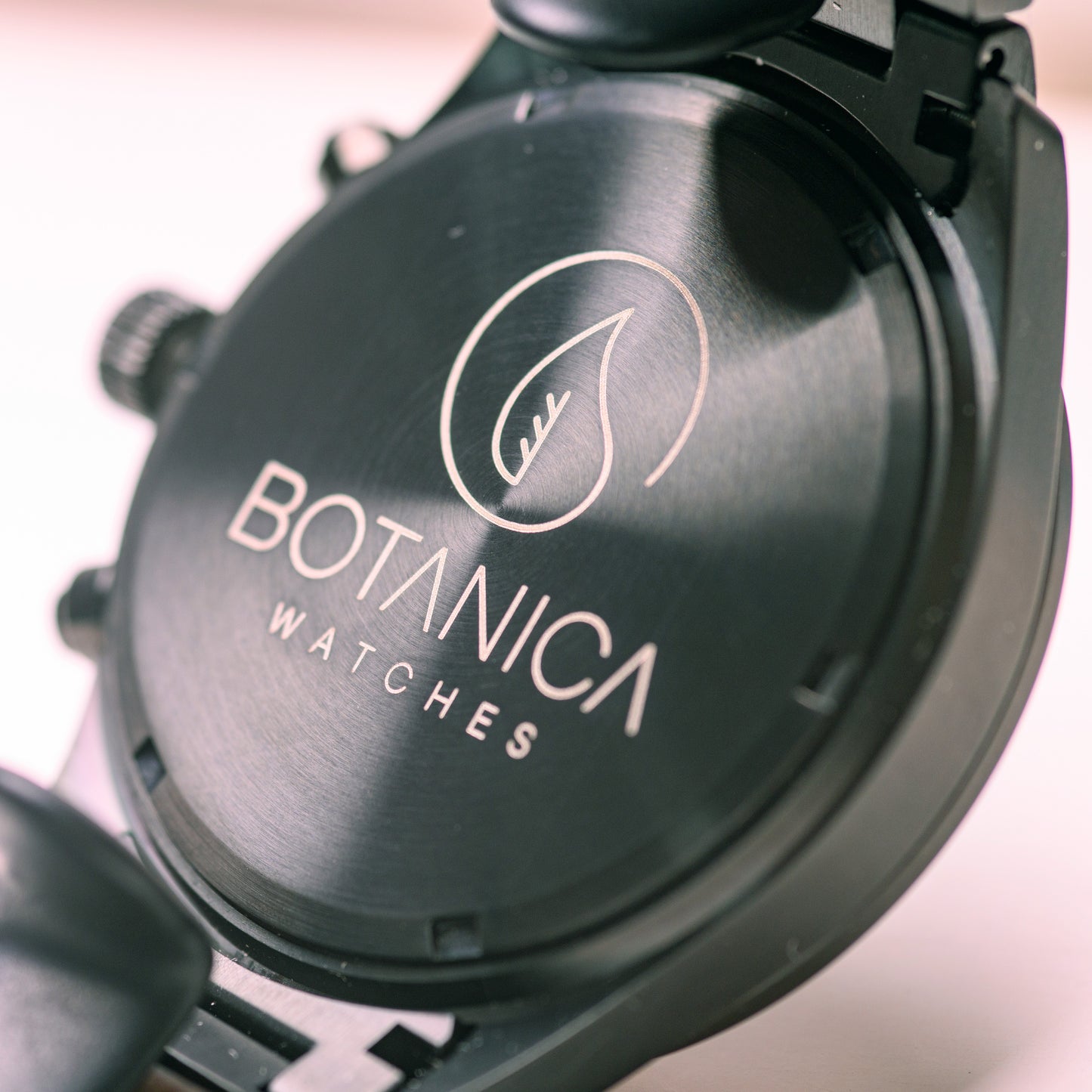 A detail of the back sealed casing of the waterproof chronograph watch highlighting the botanica logo