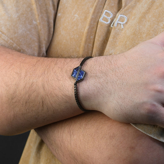 Person wearing a blue beaded bracelet on a beige shirt with 'BEAR' logo.