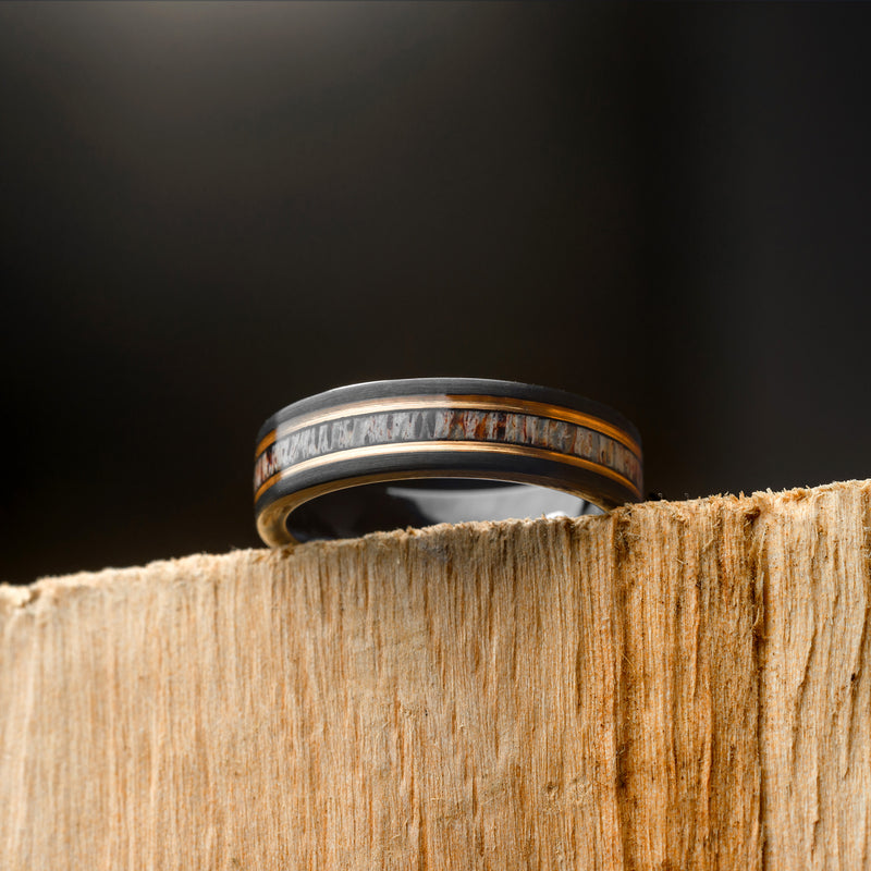 Ring with Deer Antler Inlay and a Rosegold band on a wooden block against a dark background