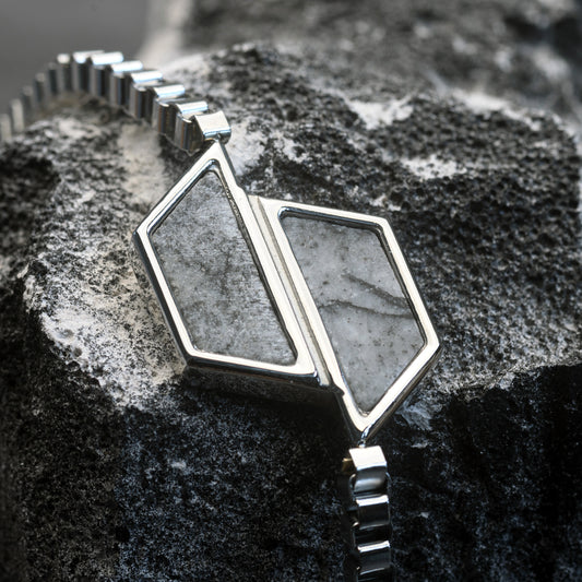 Silver geometric pendant on a dark stone surface