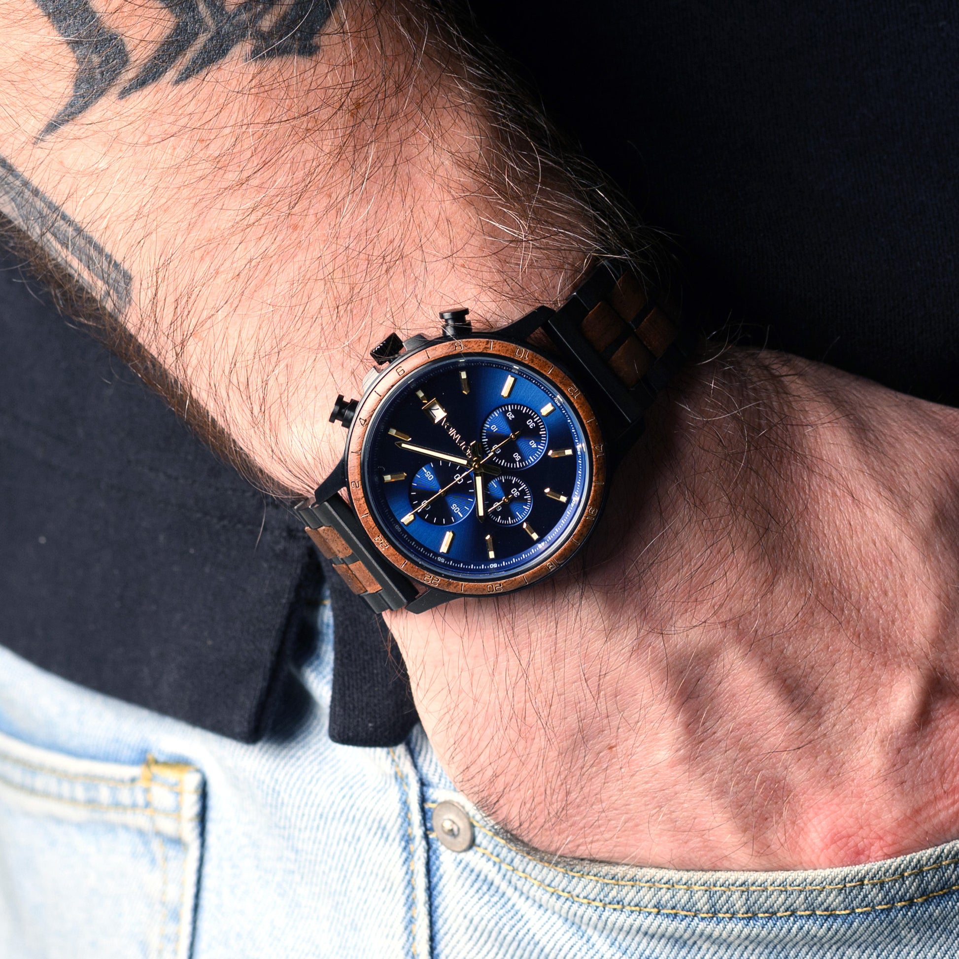 Close-up of a wrist wearing a wooden watch with a blue face.