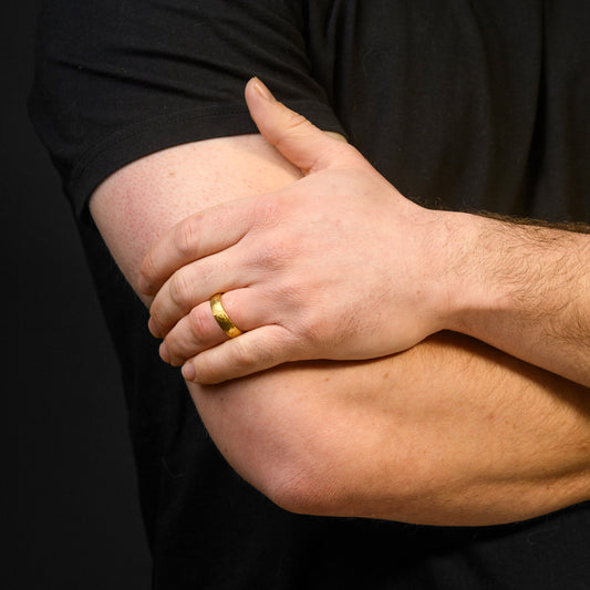 Hand with a gold ring on a black background