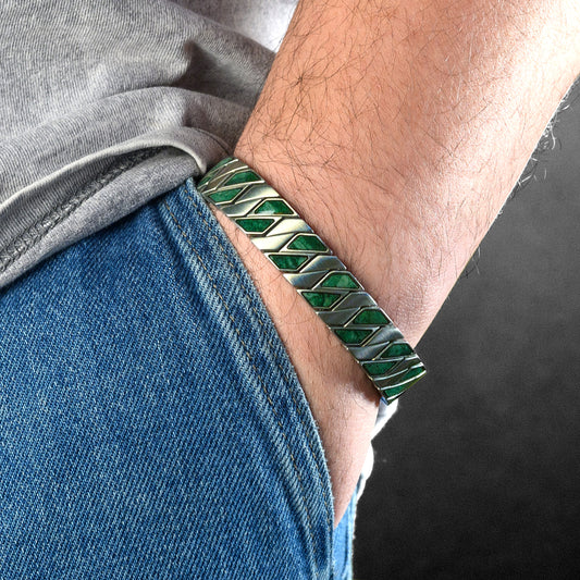 Person wearing a green and silver bracelet on a dark background