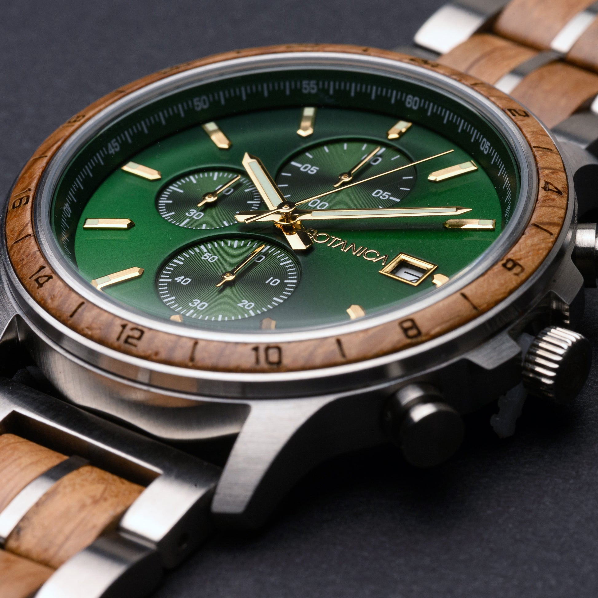 Watch with green face and wooden strap on a dark background
