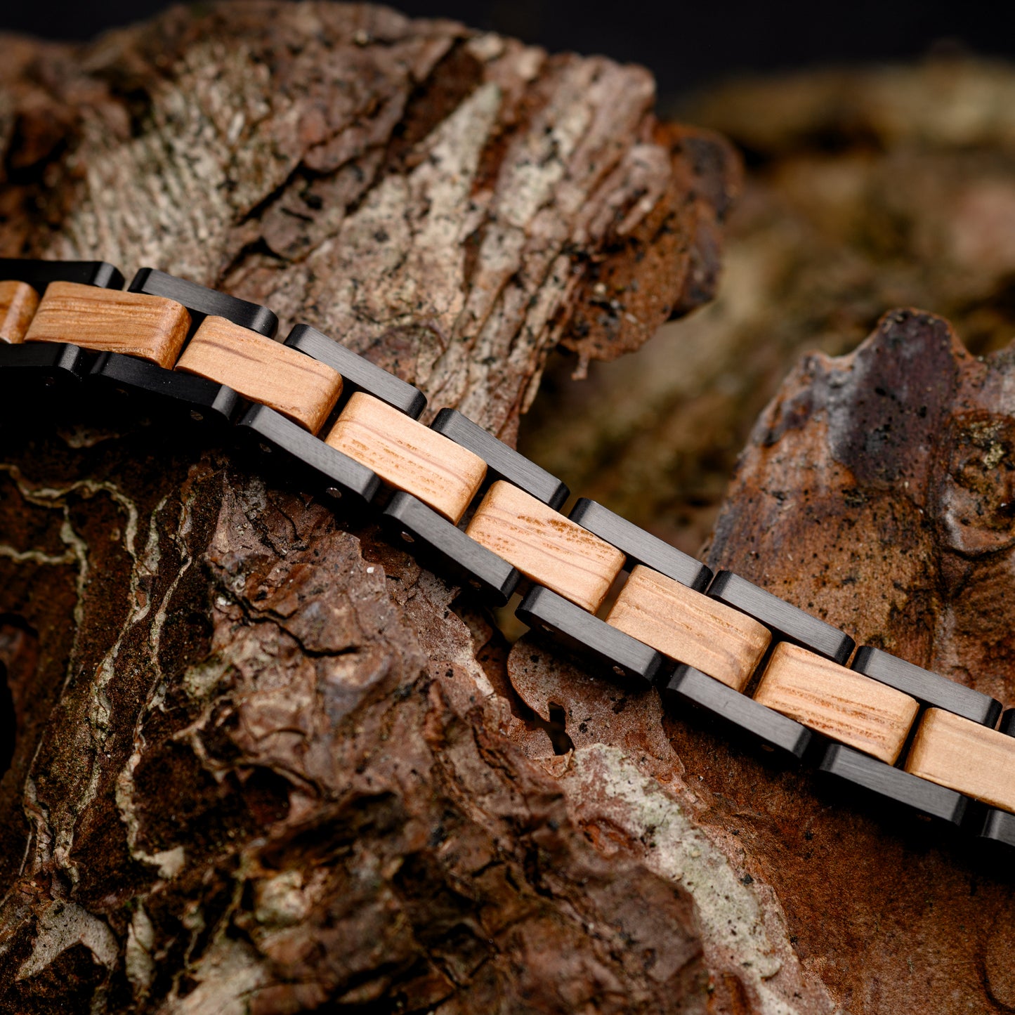 A Mens Bracelet made from Whiskey Wood and Black Tungsten Steel Resting on a piece of Drift Wood