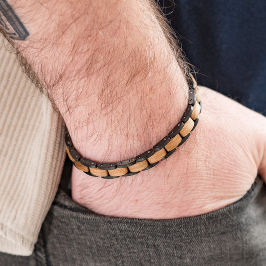 Man with hand in pocket with wood and steel link adjustable bracelet on, tatoo and close up of the arm
