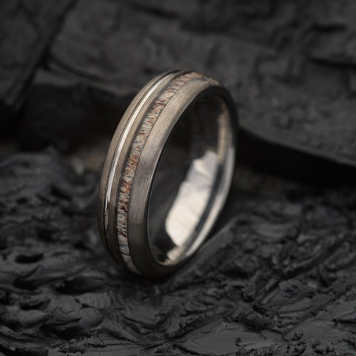 Mens Dual Groove 6mm Deer antler and tungsten steel ring with silver band sitting on a Charcoal Base