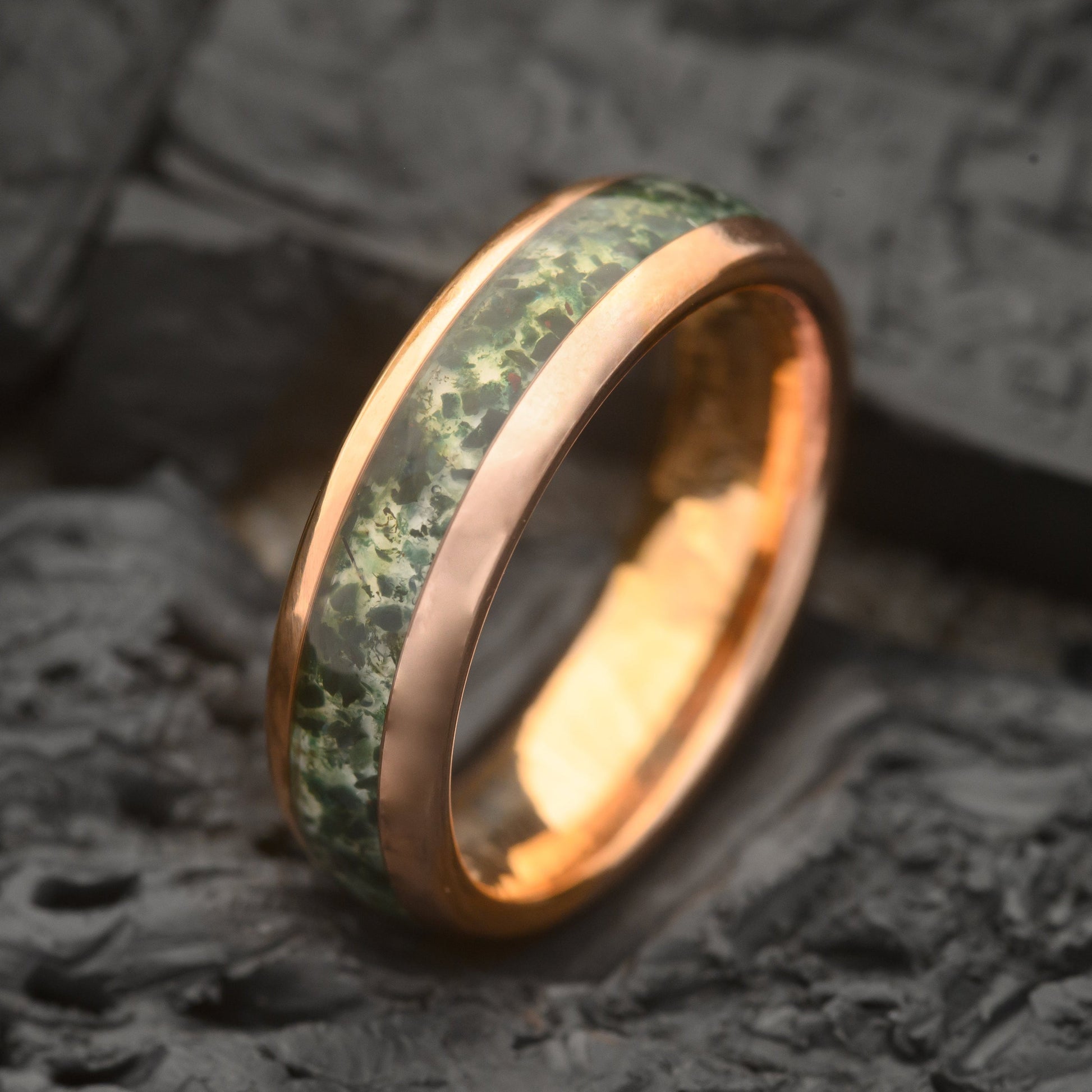 A Single Groove 6mm Moss Agate Tungsten Steel Ring sitting on a bed of Charcoal