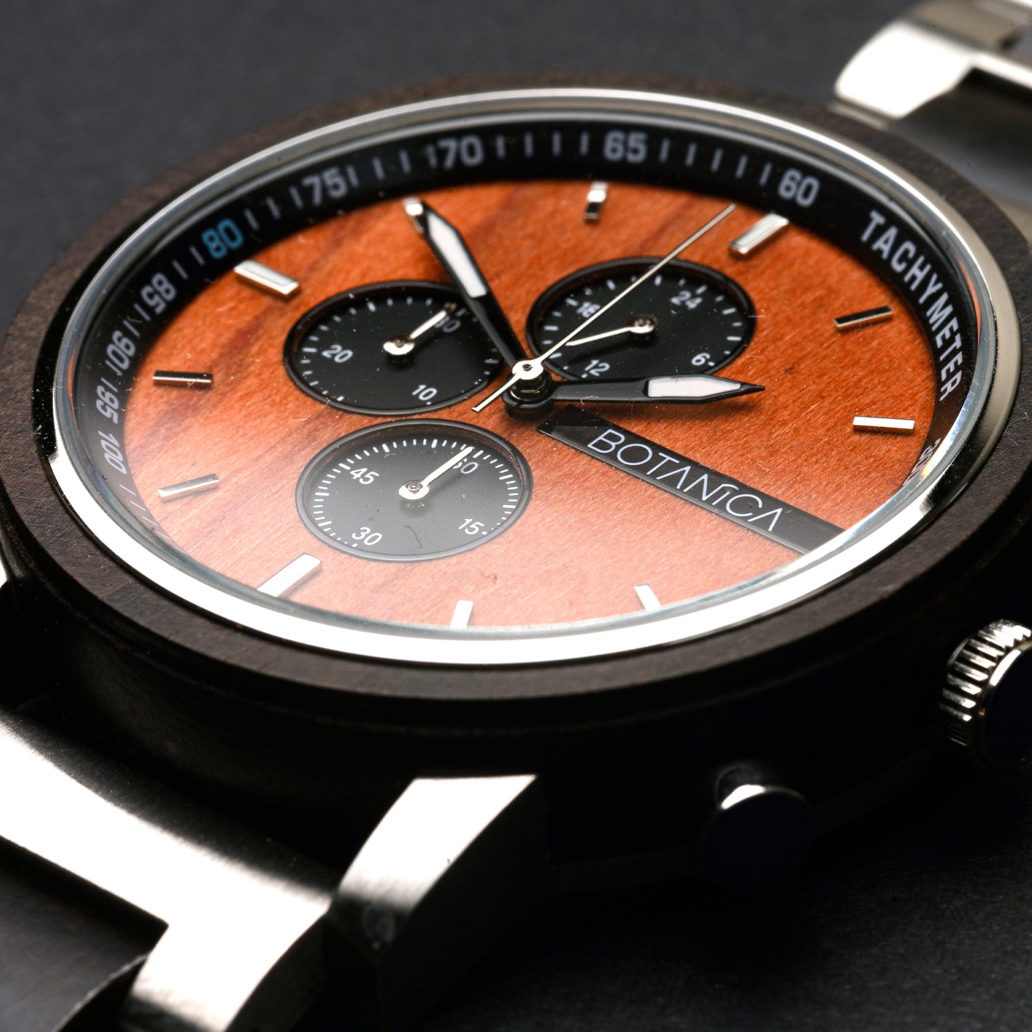 Close-up of a Sandalwood watch with a wooden face and 'BOTANICA' branding on a dark background