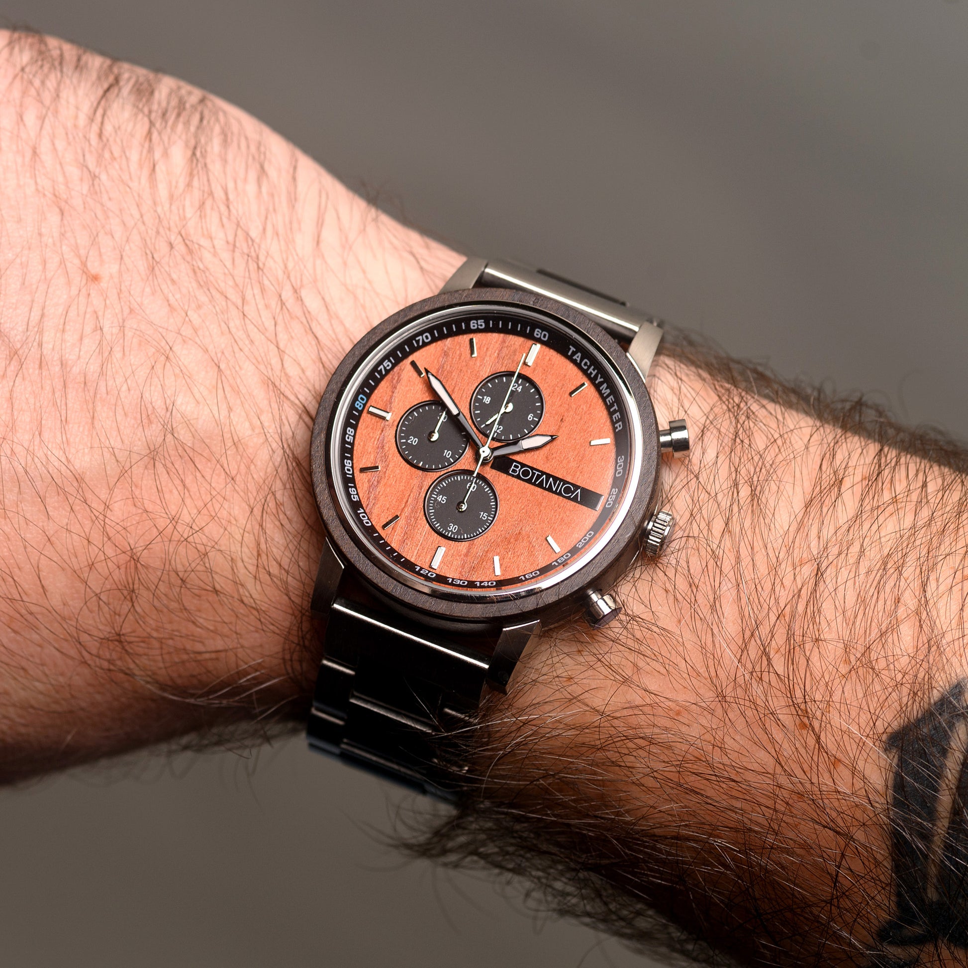 Wrist wearing a watch with a detailed face on a neutral background