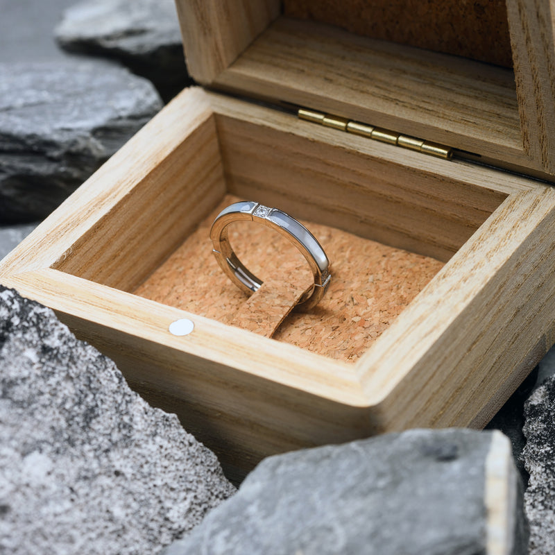 Silver ring in a wooden box with a natural stone background