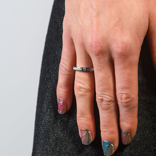 Hand with a silver ring on a gray background