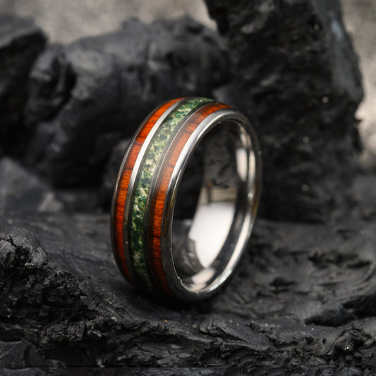 Silver tungsten ring with moss agate and rosewood inlays resting on a stone background for men or women