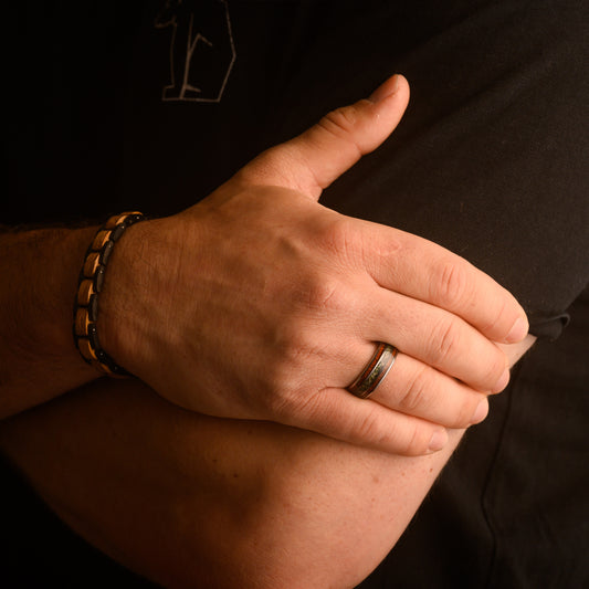 close up of man holding arm wearing a natural ring and bracelet 