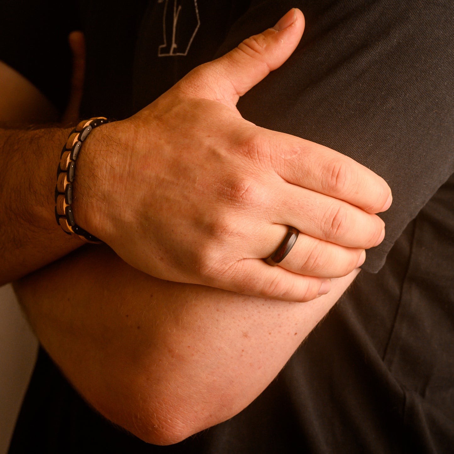 man holding arm wearing a black and red ring with bracelet on wrist