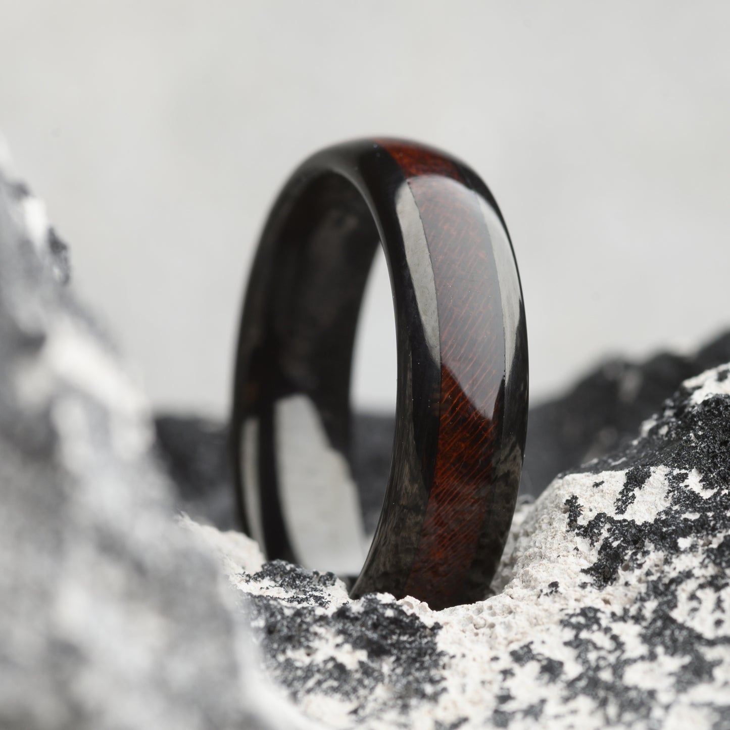 tungsten ring with rosewood inlay sitting on stone