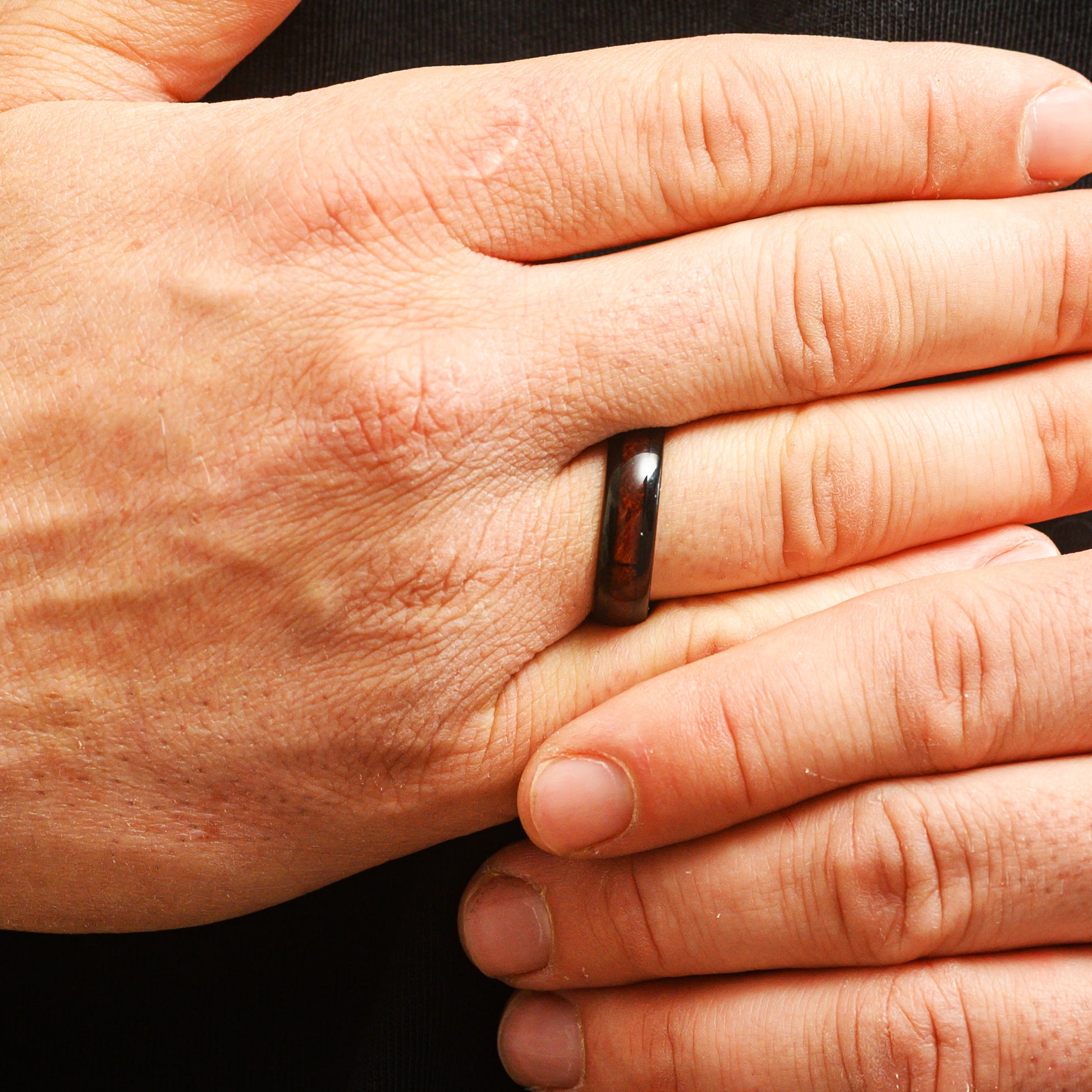 man wearing black ring with rosewood inlay close up of fingers
