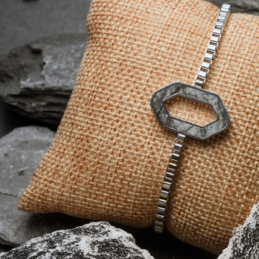 Silver bracelet with a Geometric Stone pendant  on a textured fabric surface with rocks in the background