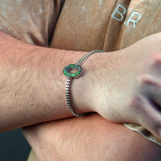 Close-up of a wrist wearing a green gemstone bracelet with a blurred background