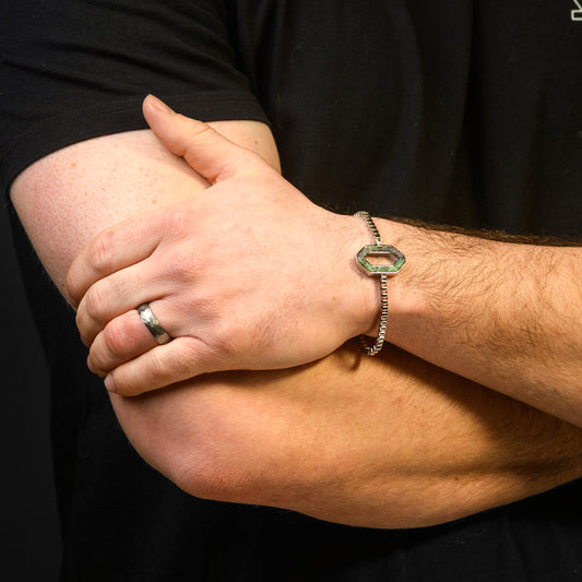Close-up of a person's arm with a bracelet and ring on a black background