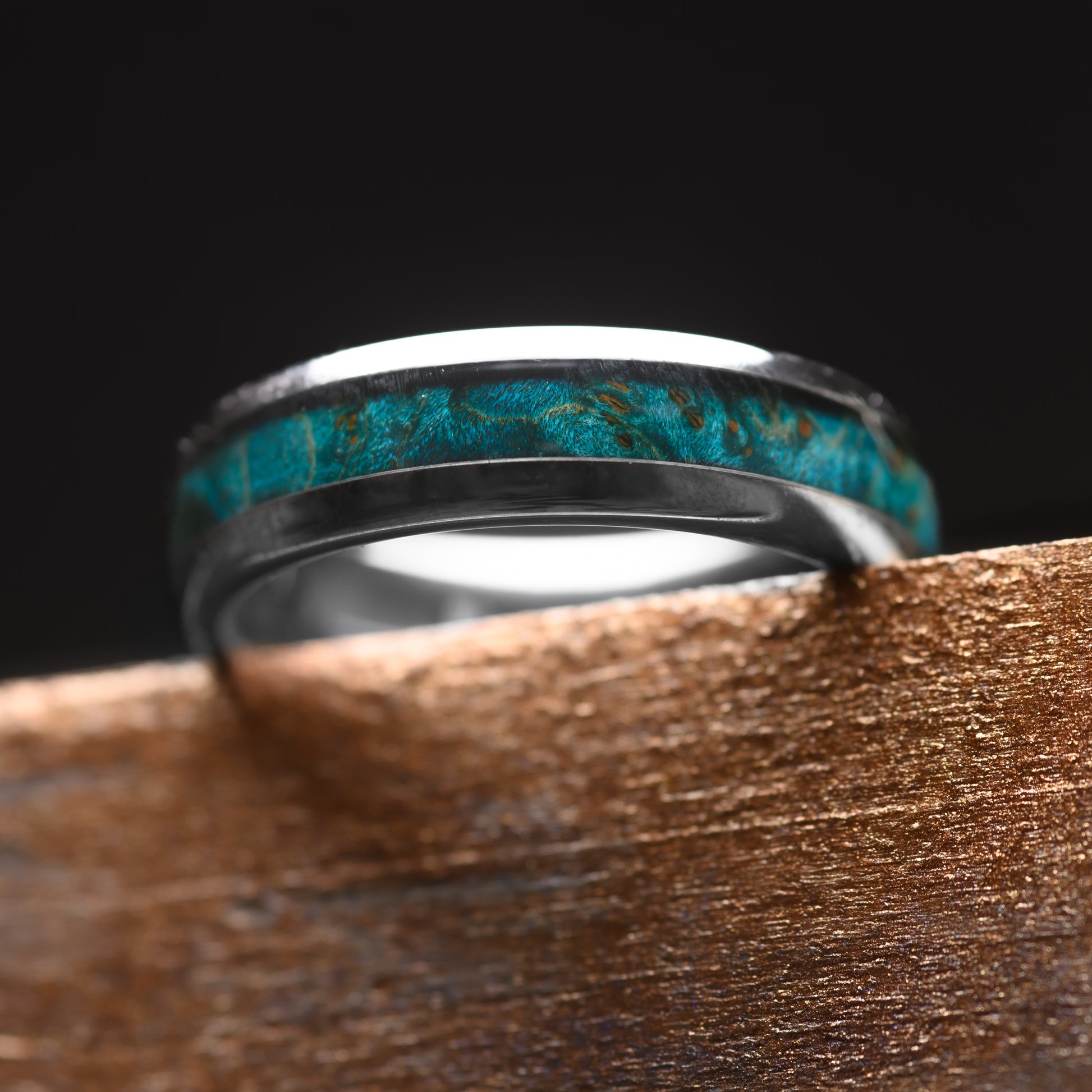 A Silver Tungsten Steel single groove ring with Canadian Maple inlay 6mm resting on a worktop bench