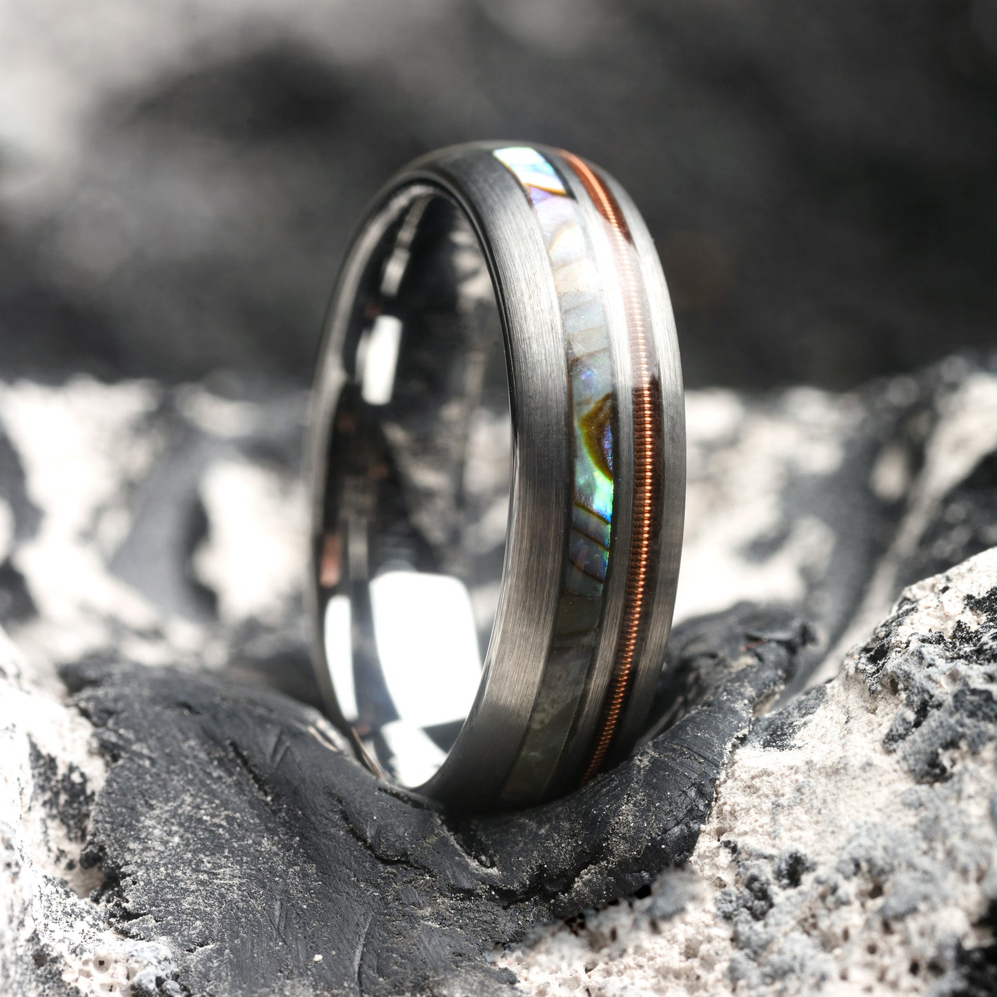 Silver ring with an abalone shell inlay on a textured surface