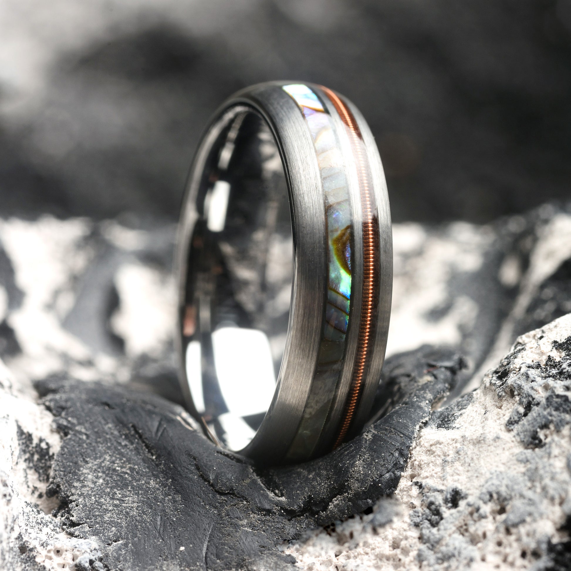 Silver ring with an abalone shell inlay on a textured surface