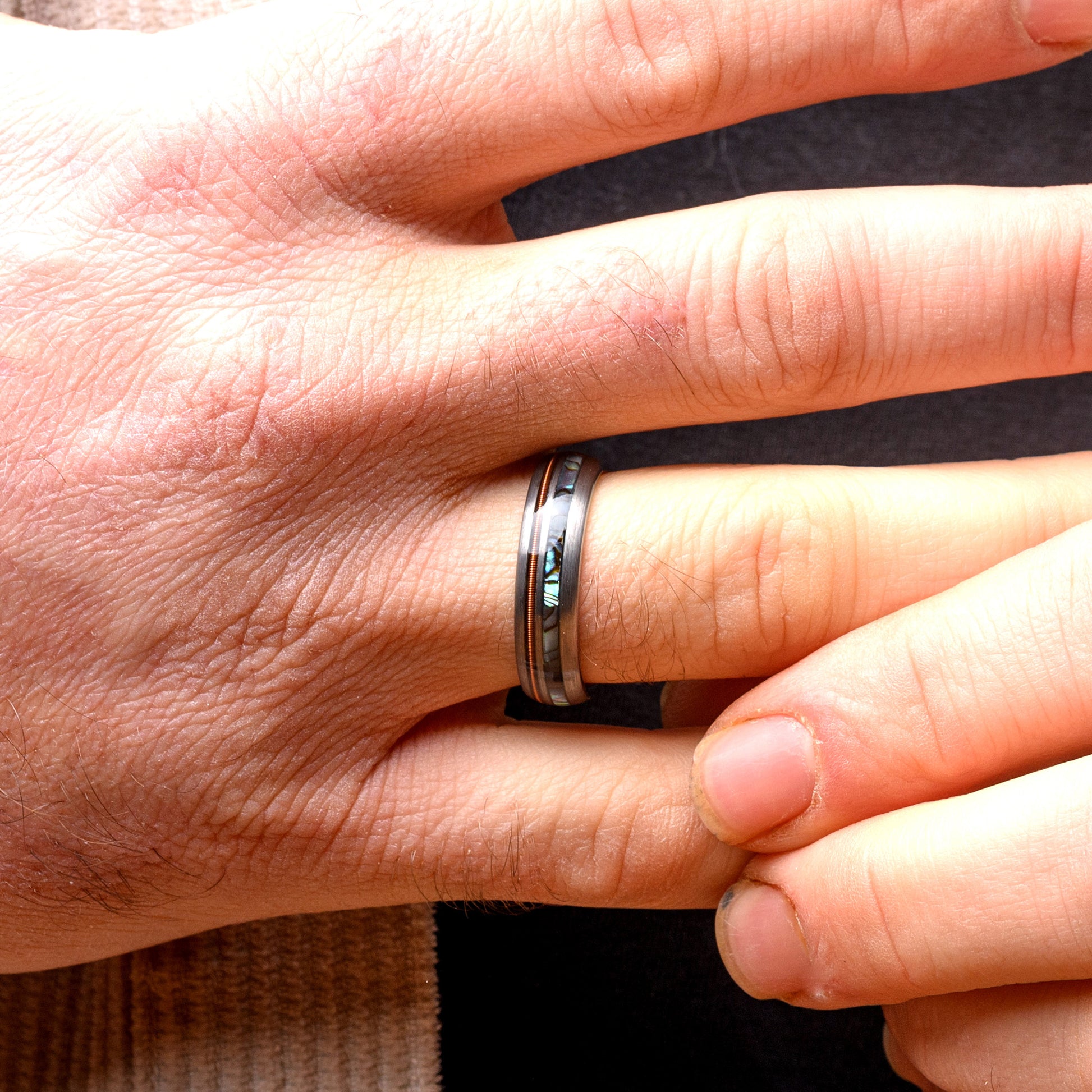 Close-up of a hand wearing a silver ring with a blurred background