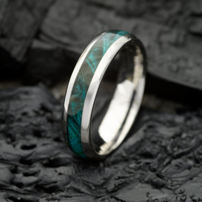 A 6mm Silver Tungsten Steel single groove ring with Canadian Maple inlay resting on a bed of Charcoal