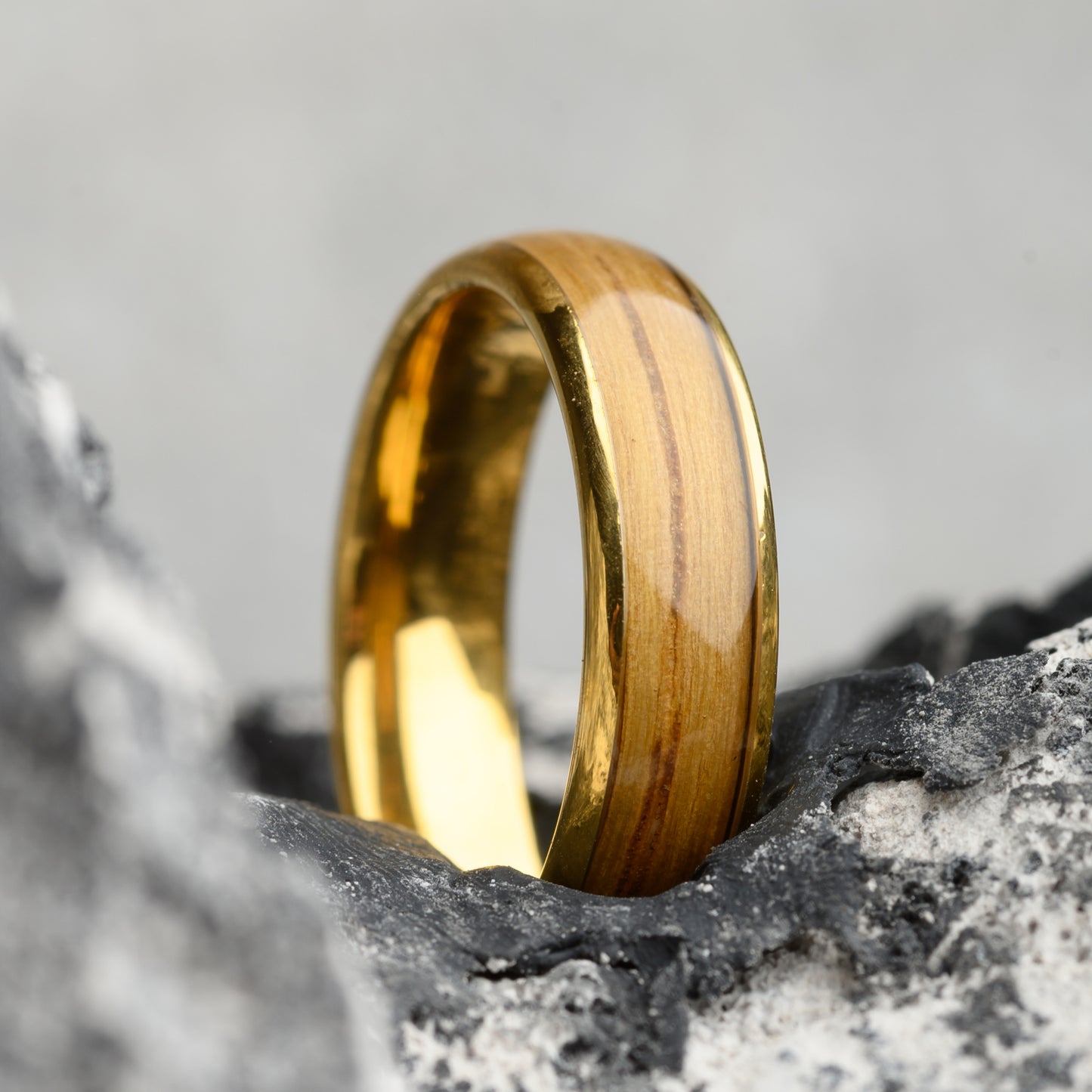 gold ring with wood inlay on stone background