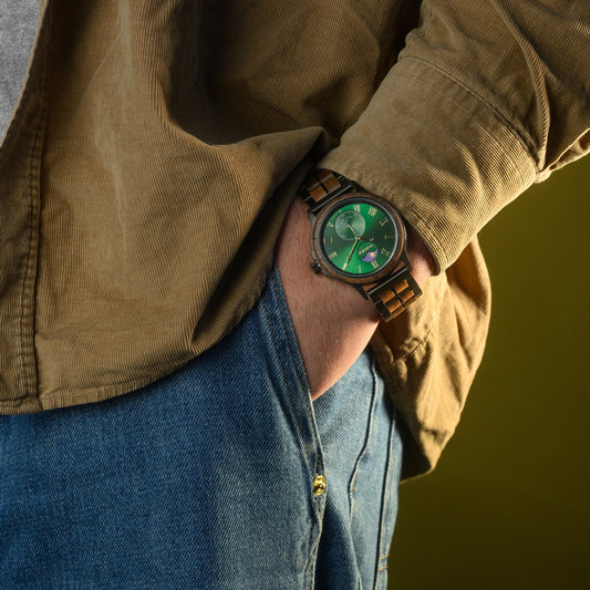 Person wearing a green watch with a woodlink strap, standing against a yellow background.