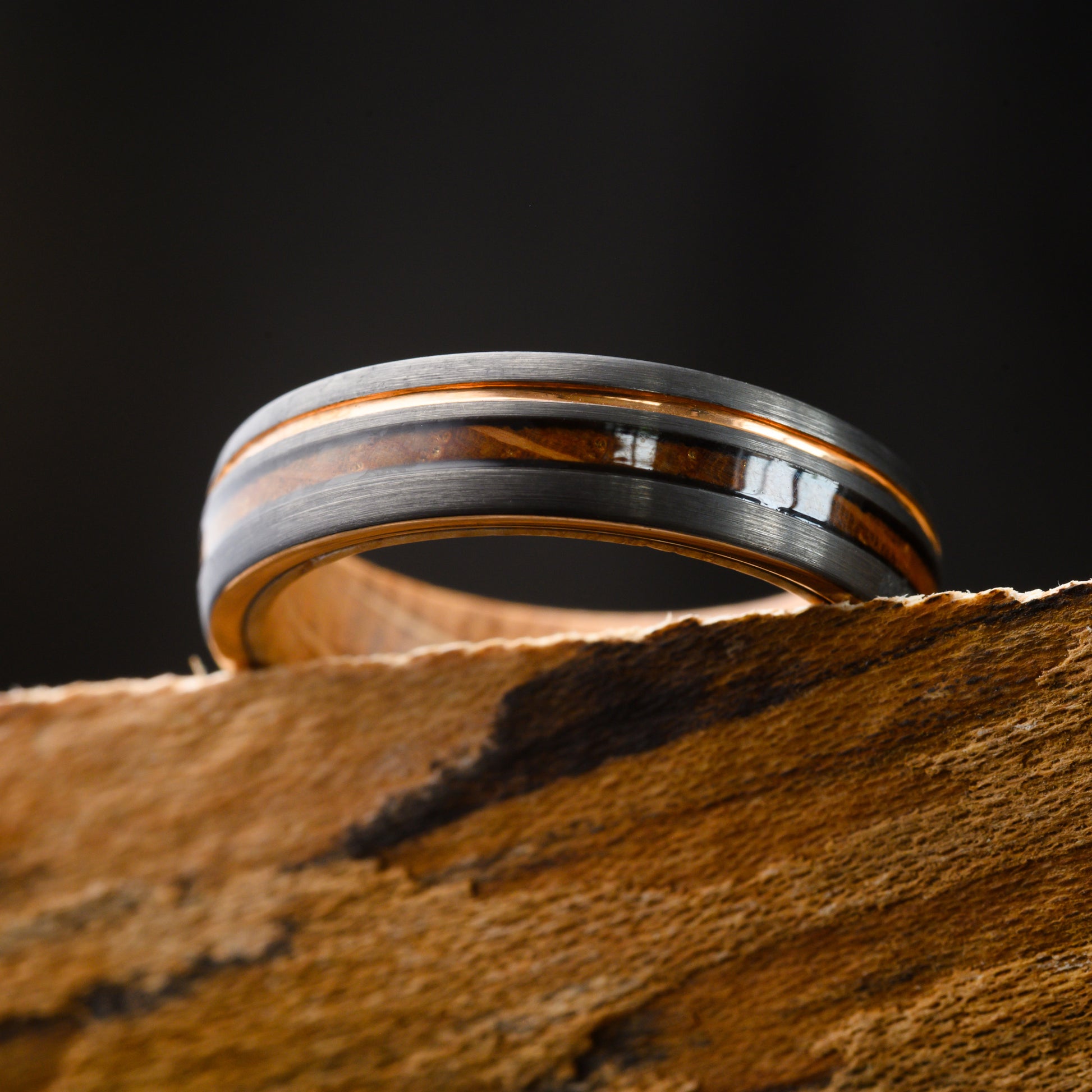 wood and grey metal inlay ring resting on shelf with black background