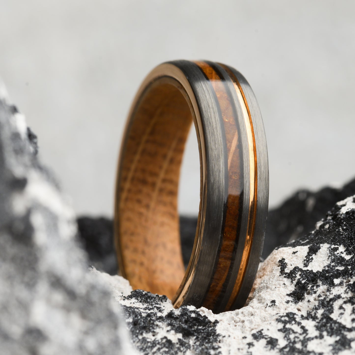 ring with wood inlay and steel resting on stone background for men