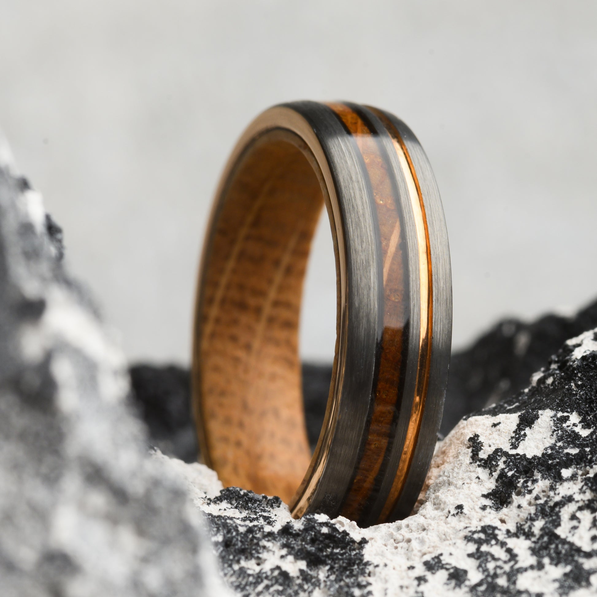 ring with wood inlay and steel resting on stone background for men