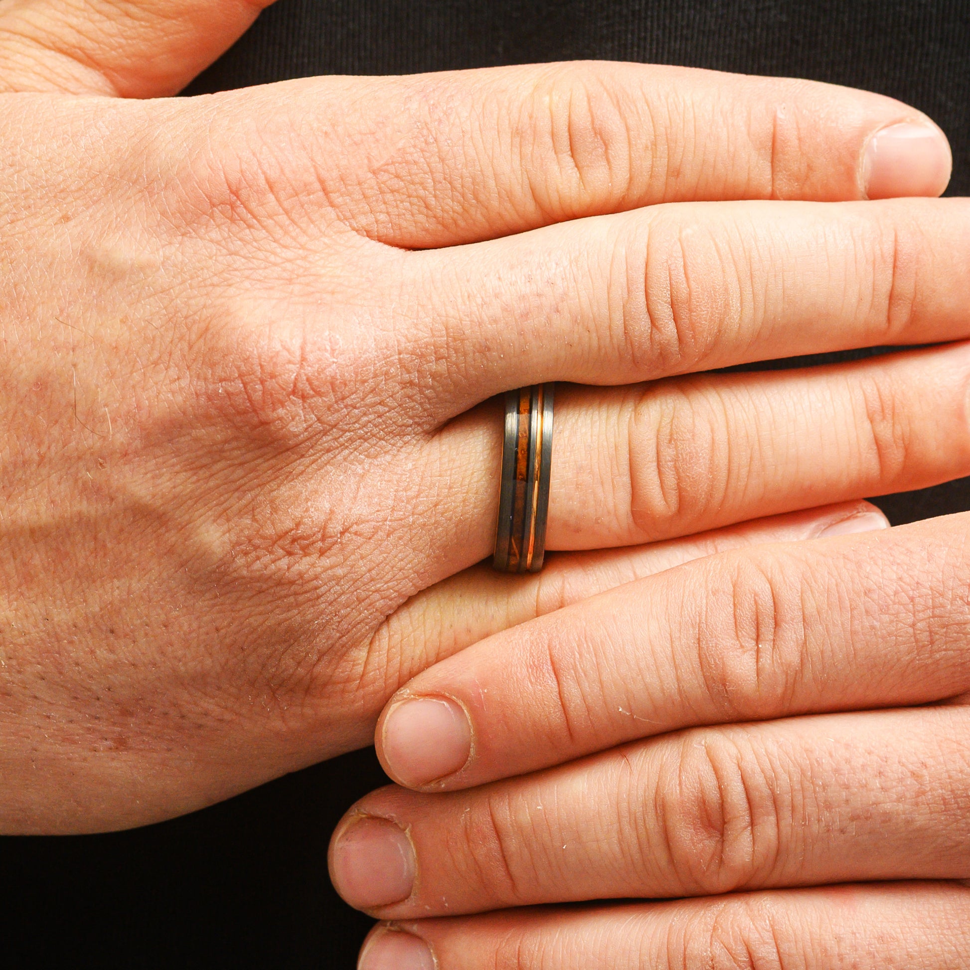 man wearing natural ring with wood inlay close up of fingers