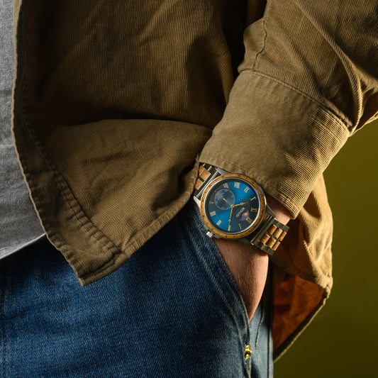 Person wearing a brown jacket and blue jeans with a watch on their wrist.