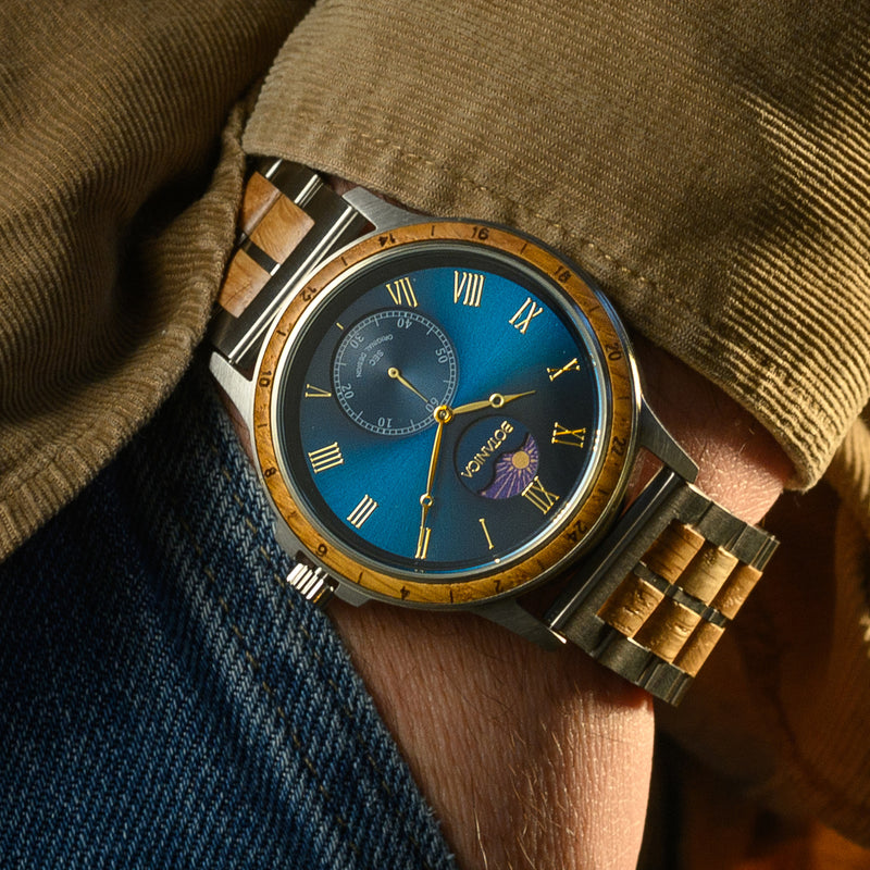 Close-up of a wrist wearing a detailed watch with a blue face and wooden strap.