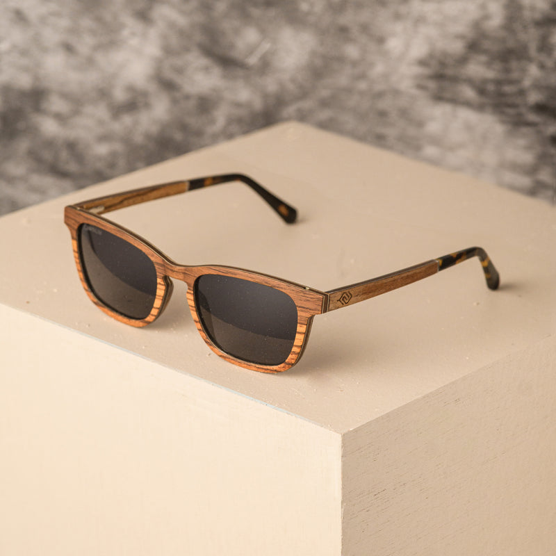 Skinny rectangular wooden sunglasses with a layered Zebrano and walnut veneer, aluminum reinforcement, and polarized lenses.